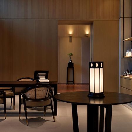 The Ruma Hotel And Residences Kuala Lumpur Exteriér fotografie The photo shows a modern, minimalist interior space. It features a wooden wall with soft lighting, enhancing a calm atmosphere. In the foreground, there is a round table with a uniquely designed lamp on it. Surrounding the table, there are stylish wo