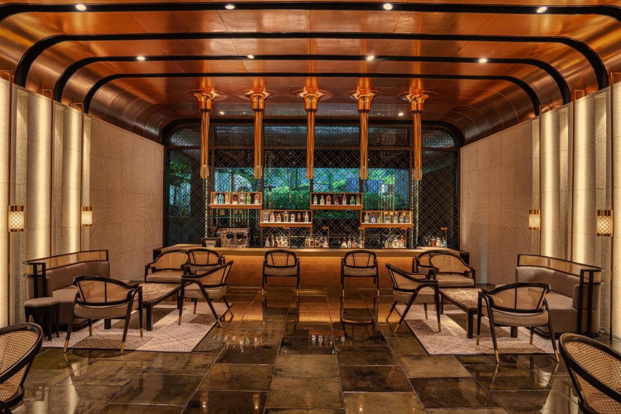 The Ruma Hotel And Residences Kuala Lumpur Exteriér fotografie The photo shows a stylish interior of a bar or lounge area. The space features a combination of elegant materials, including polished metal accents and warm lighting. A wooden bar counter is centrally located, with several shelves displaying various 